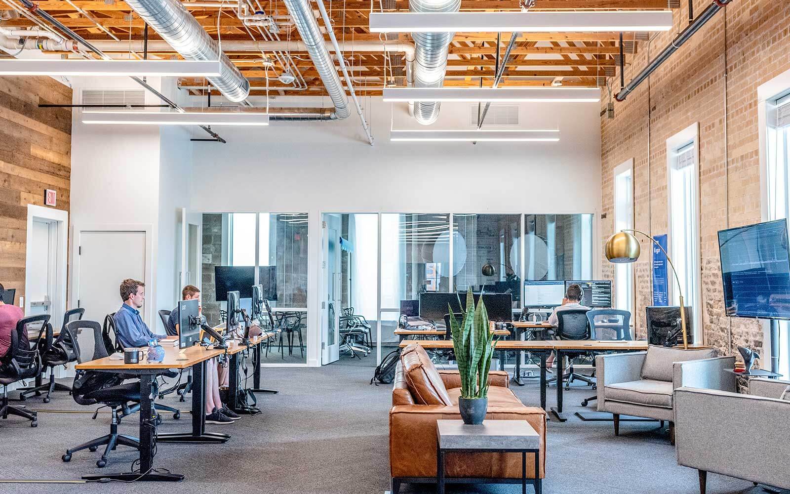 Employees work in front of their computers in a modern office environment.